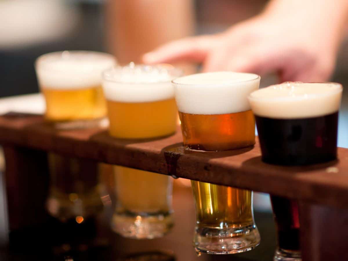 Close-up of a variety of beer glasses on a wooden sampler tray, each containing different types and colors of beer. This image highlights the diversity of craft beers available in San Francisco’s brewery scene, a favored activity for things to do in San Francisco.