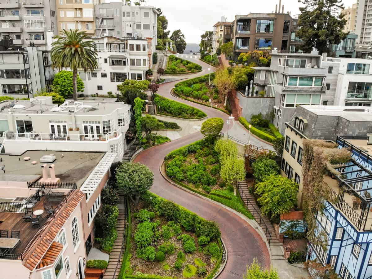 An aerial view of Lombard Street, known for its steep, one-block section with eight hairpin turns. Surrounded by lush greenery and beautiful homes, walking or driving down Lombard Street is a popular activity among things to do in San Francisco.