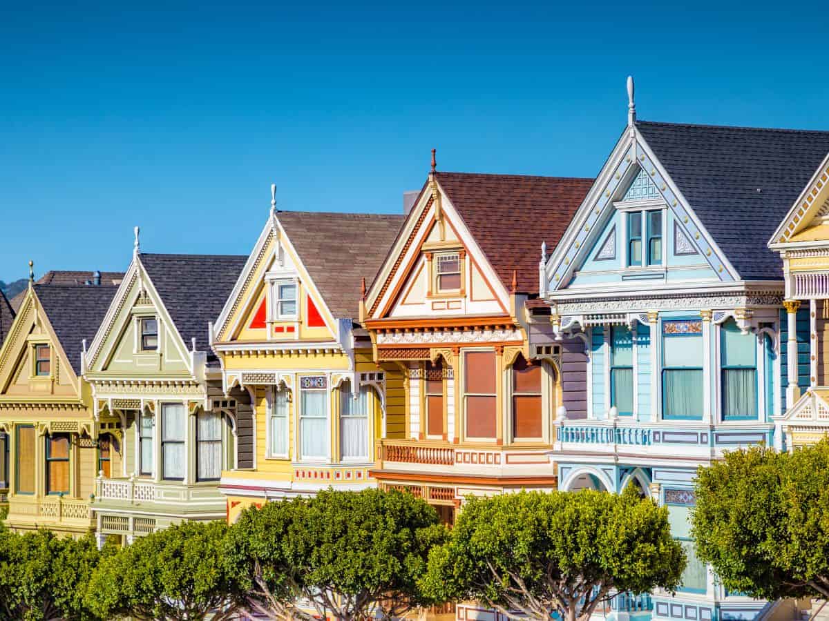The iconic "Painted Ladies" Victorian houses in San Francisco, set against a blue sky. Touring the Painted Ladies and the surrounding Alamo Square is a popular activity for architecture enthusiasts in San Francisco.