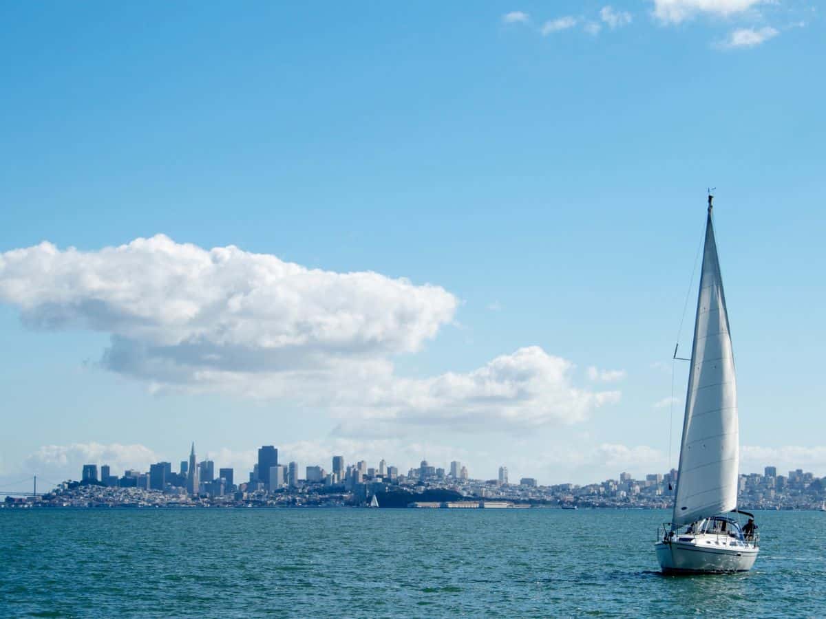 A sailboat on the San Francisco Bay with the city skyline in the background, offering a peaceful escape and a beautiful view, making sailing one of the recommended things to do in San Francisco.