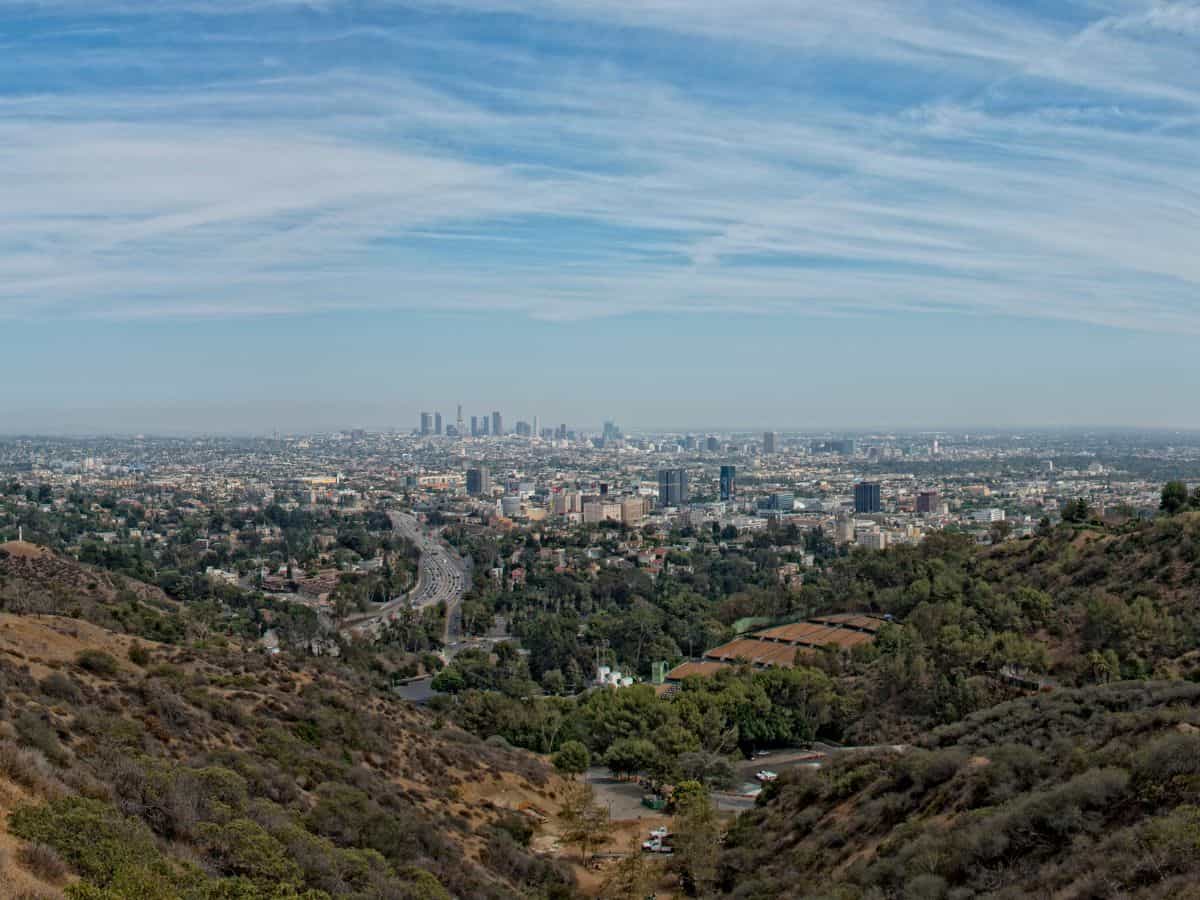 Panoramic view of Los Angeles from Mulholland Drive, showcasing the expansive cityscape against a backdrop of mountains and clear skies, ideal for scenic drives and views.