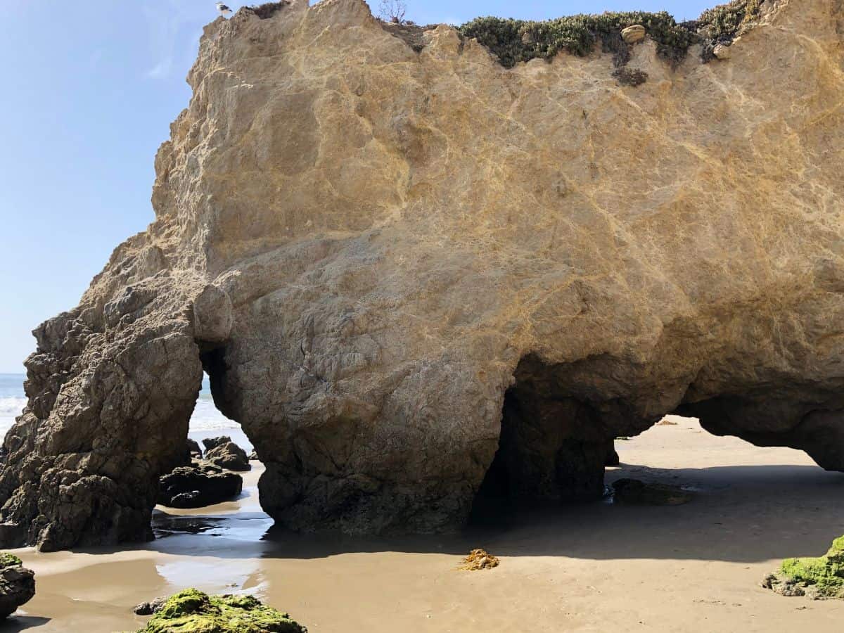 View of El Matador Beach featuring distinctive rocky arches and caves along the sandy shore, a serene and picturesque thing to do in Los Angeles for beach lovers.