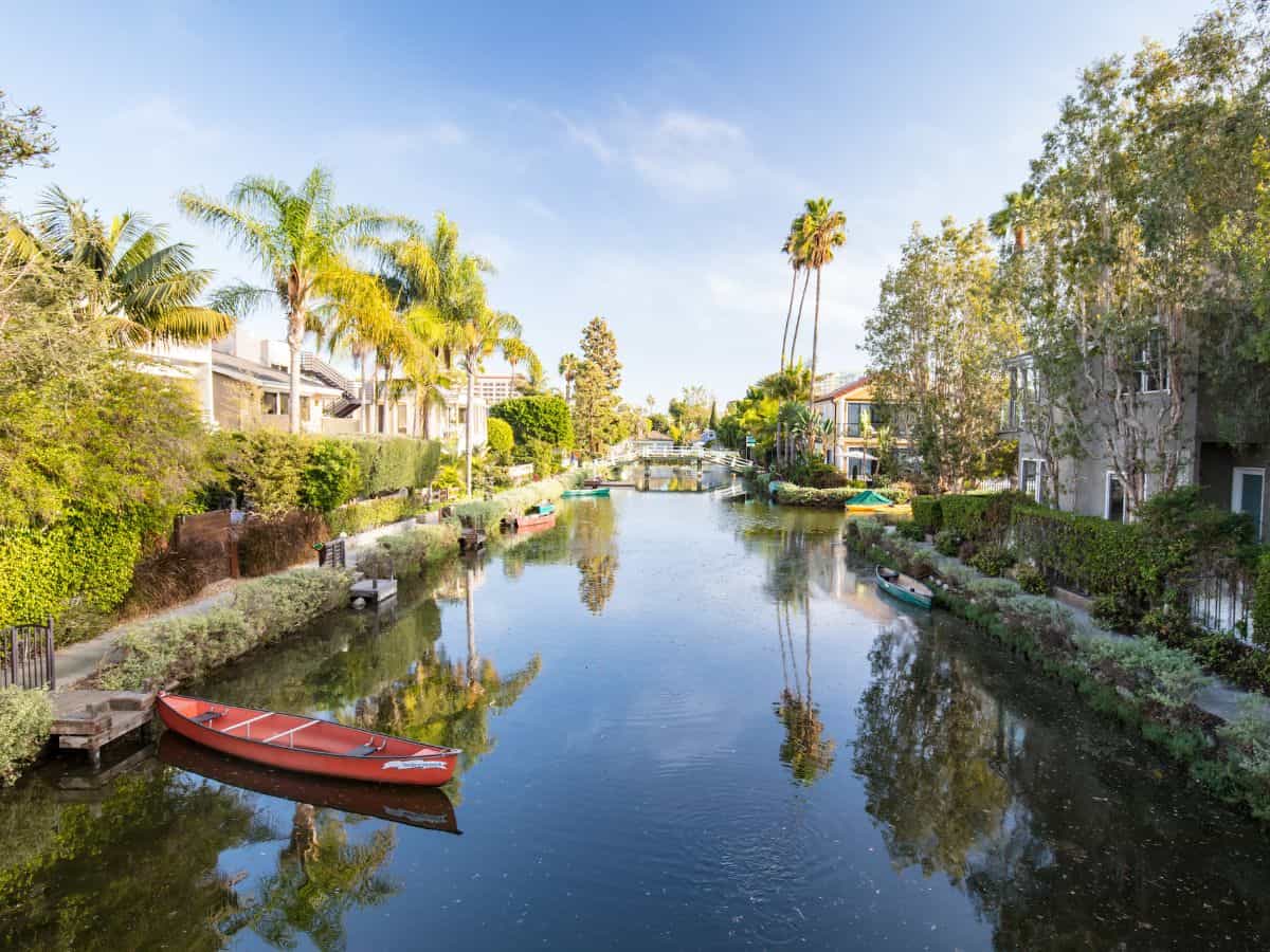 Peaceful view of the Venice Canals in Los Angeles with charming houses and lush gardens reflecting in the calm waters, a unique and relaxing thing to do in Los Angeles.