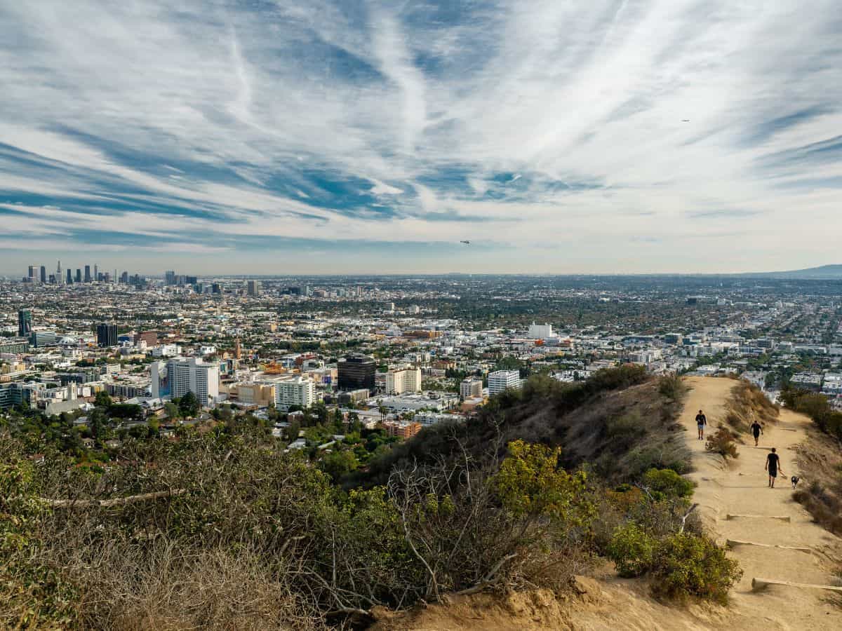A sweeping view from Runyon Canyon Park overlooking the expansive Los Angeles cityscape, with scattered buildings and clear skies.