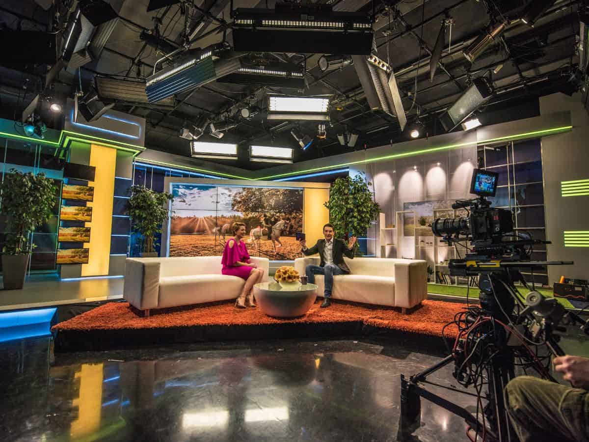 A modern TV studio set in Los Angeles, showing a lively interview setup with hosts and a guest, illustrating behind-the-scenes tours that could be interesting things to do in Los Angeles.