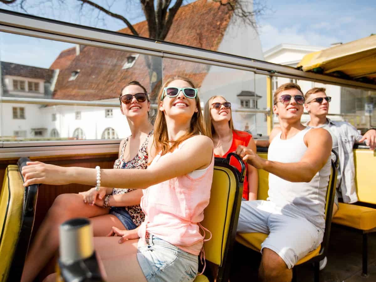 Tourists enjoying a guided bus tour in Los Angeles, seated and smiling under a clear sky, an enjoyable and informative thing to do in Los Angeles for first-time visitors.