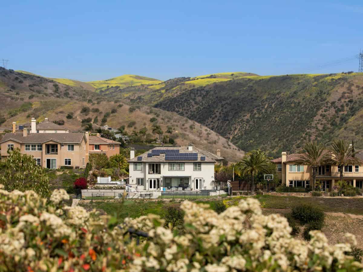 A view of luxurious homes nestled in the rolling California hills, surrounded by sparse vegetation. Limited available land for new development drives up real estate prices, illustrating why California is so expensive.