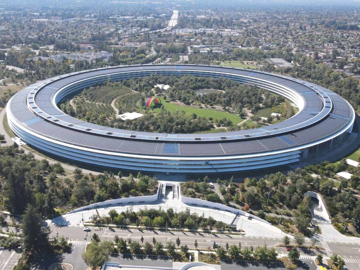 An aerial view of a large, modern circular corporate building surrounded by greenery. California, being home to many successful corporations, boosts its economic appeal but also drives up living costs, showing why California is so expensive.
