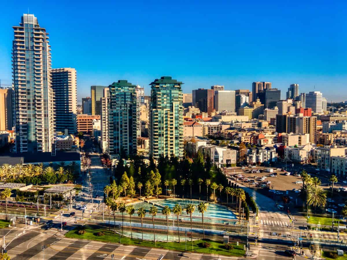 An aerial view of a bustling downtown area with skyscrapers and modern buildings. Strict building codes and regulations make construction more costly, affecting housing prices and explaining why California is so expensive.