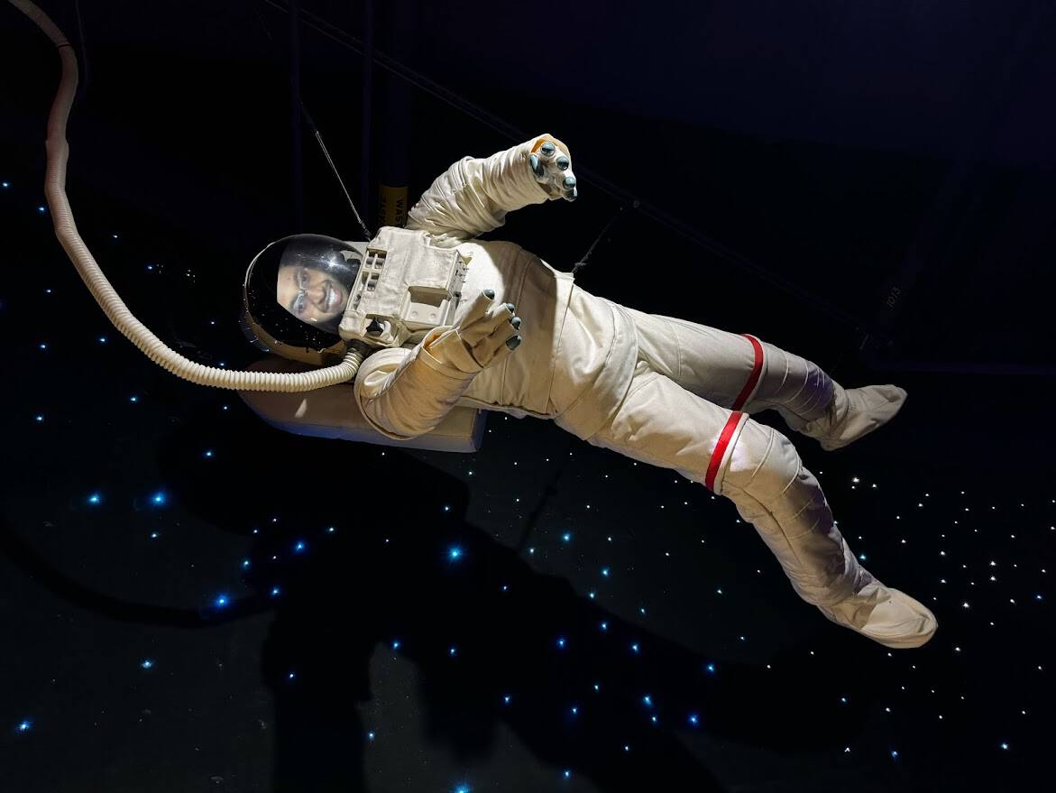 Kiran posing in an astronaut suit exhibit at The Tech Interactive.