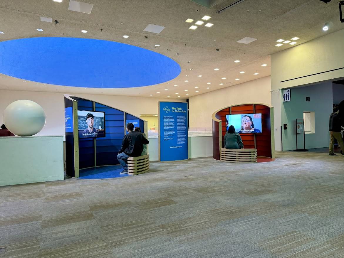 An open exhibit area with multimedia displays featuring stories of innovative solutions addressing global challenges.