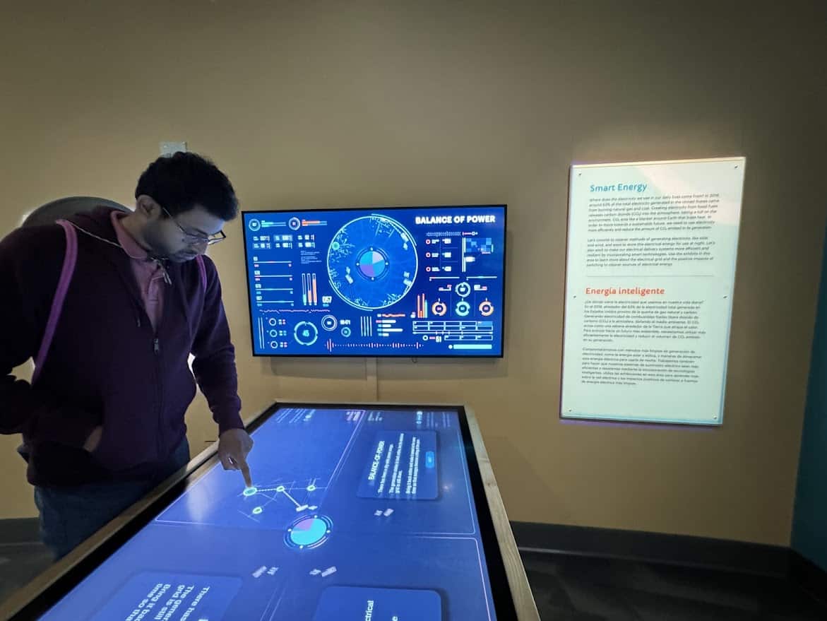 Kiran engages with the Balance of Power exhibit, exploring power grid simulations to learn about energy management and sustainability.