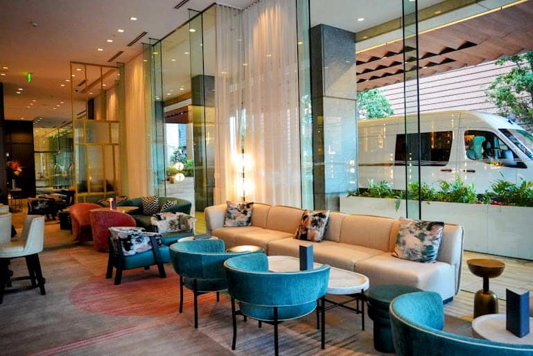 The luxurious lounge area of the St. Regis San Francisco, showcasing plush seating in elegant jewel tones and a sleek, modern design with floor-to-ceiling windows overlooking the city.