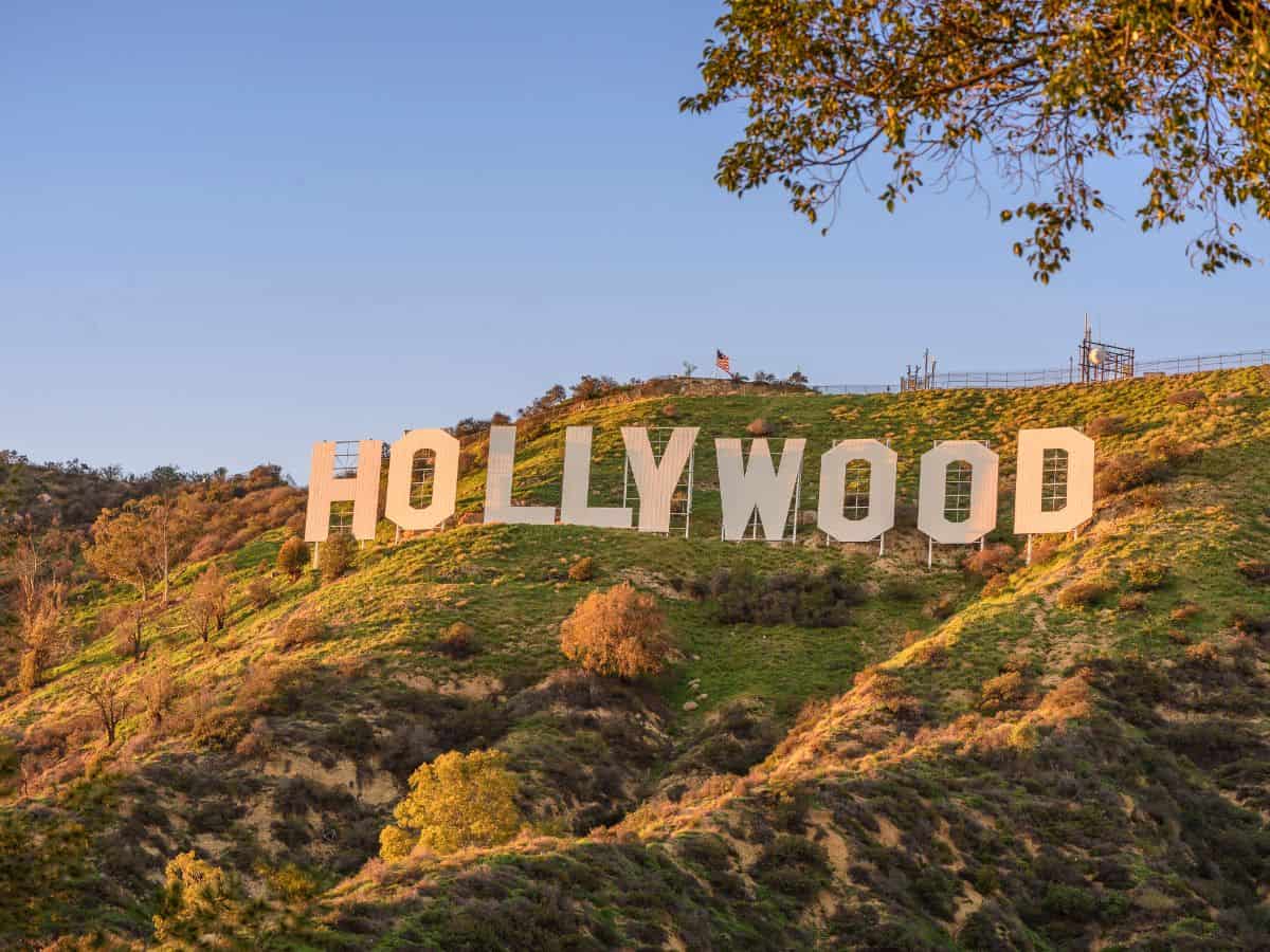 A stunning view of the iconic Hollywood sign perched on a sunlit hillside, surrounded by lush greenery under a clear blue sky. This world-famous symbol of the entertainment industry highlights Los Angeles' global allure and cultural prestige, contributing to the discussion: Why Is Los Angeles So Expensive? The Truth About the High Costs of Living.