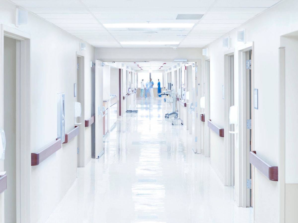 A pristine, well-lit hospital corridor with doors leading to patient rooms and medical equipment visible in the distance. Healthcare professionals can be seen working in the background, emphasizing the high standards of medical care in Los Angeles. This image highlights the premium healthcare services that contribute to the question: Why Is Los Angeles So Expensive? The Truth About the High Costs of Living.