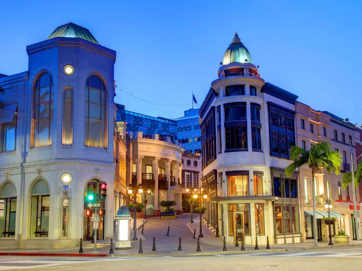 An elegant street in Beverly Hills at dusk, featuring upscale boutiques, classical architecture, and soft glowing lights. The luxurious ambiance of this affluent area highlights the lifestyle of wealthy residents, playing a significant role in the discussion: Why Is Los Angeles So Expensive? The Truth About the High Costs of Living.