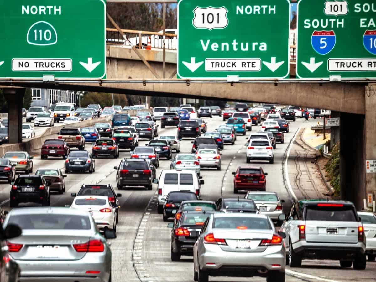 A congested Los Angeles freeway with multiple lanes of cars under green highway signs pointing toward routes 101 and 110. The heavy traffic symbolizes the city's reliance on personal vehicles, contributing to high commuting expenses and raising the question: Why Is Los Angeles So Expensive? The Truth About the High Costs of Living.