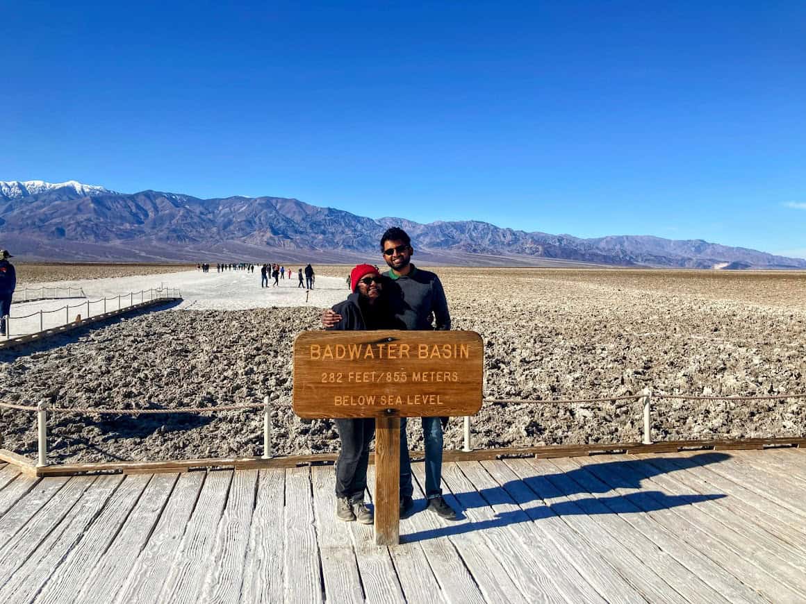 Shreeyeh and Kiran posing by the Badwater Basin sign in Death Valley National Park, marking the elevation of 282 feet below sea level.