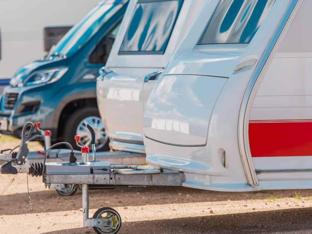 A row of camper trailers and RVs parked side by side, showcasing their hitches and streamlined exteriors.