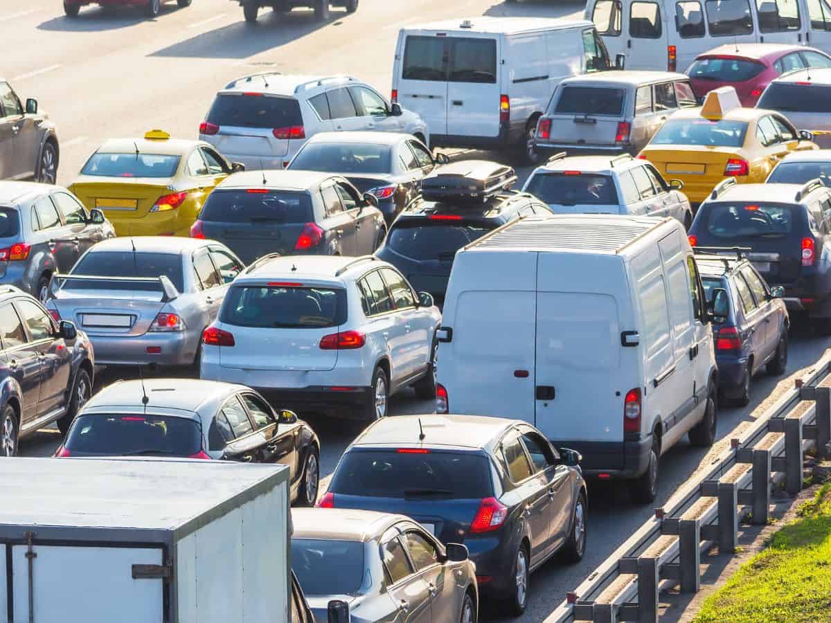 A congested highway packed with cars, taxis, and vans in multiple lanes, with vehicles closely lined up during rush hour.
