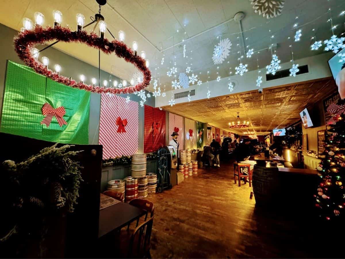 A bar decked out in holiday decorations with giant wrapped presents, hanging snowflakes, and Christmas lights, one of the festive indoor spots on the 32 Things To Do In Sacramento list.