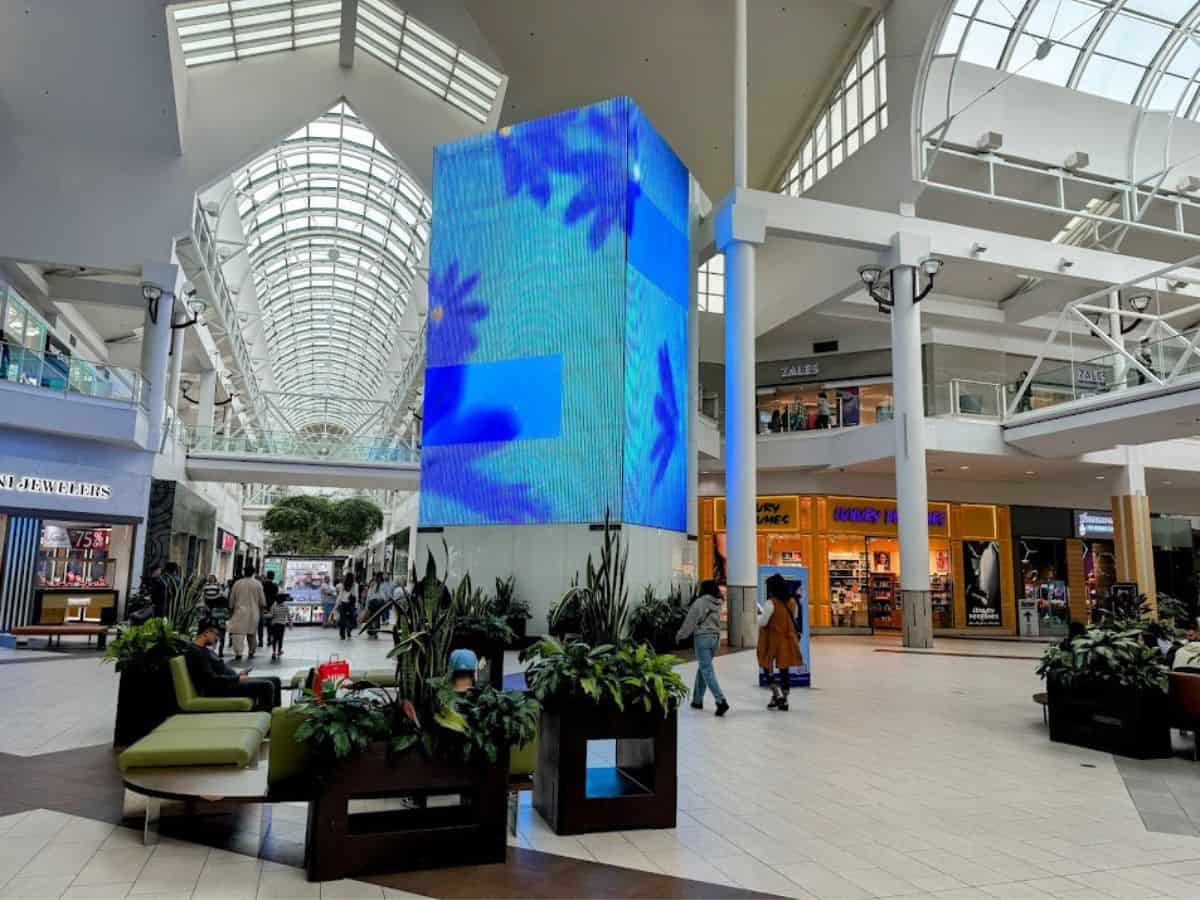 The bright and modern interior of Arden Fair Mall with a glowing digital display and shoppers walking by, a top shopping destination from the 32 Things To Do In Sacramento.