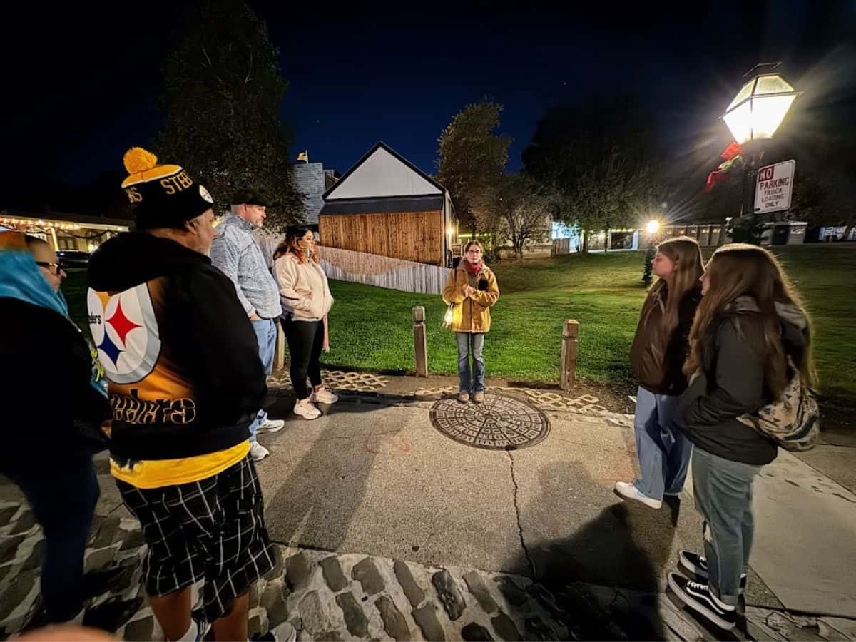 A small group gathers around a guide at night during a ghost tour in Old Sacramento, one of the more unique experiences in the 32 Things To Do In Sacramento.
