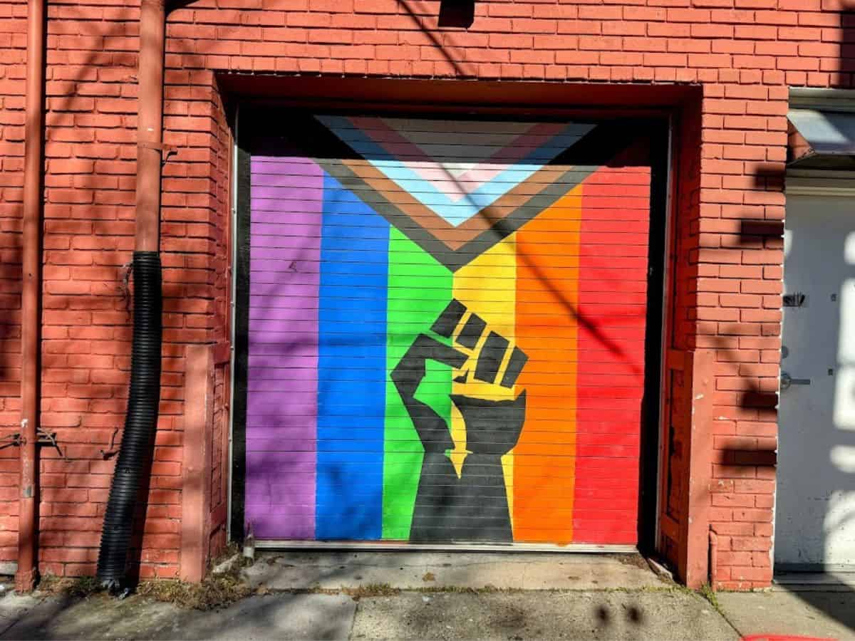 A painted mural on a brick wall shows a raised fist over a rainbow pride flag, representing Sacramento’s street art scene in the 32 Things To Do In Sacramento.
