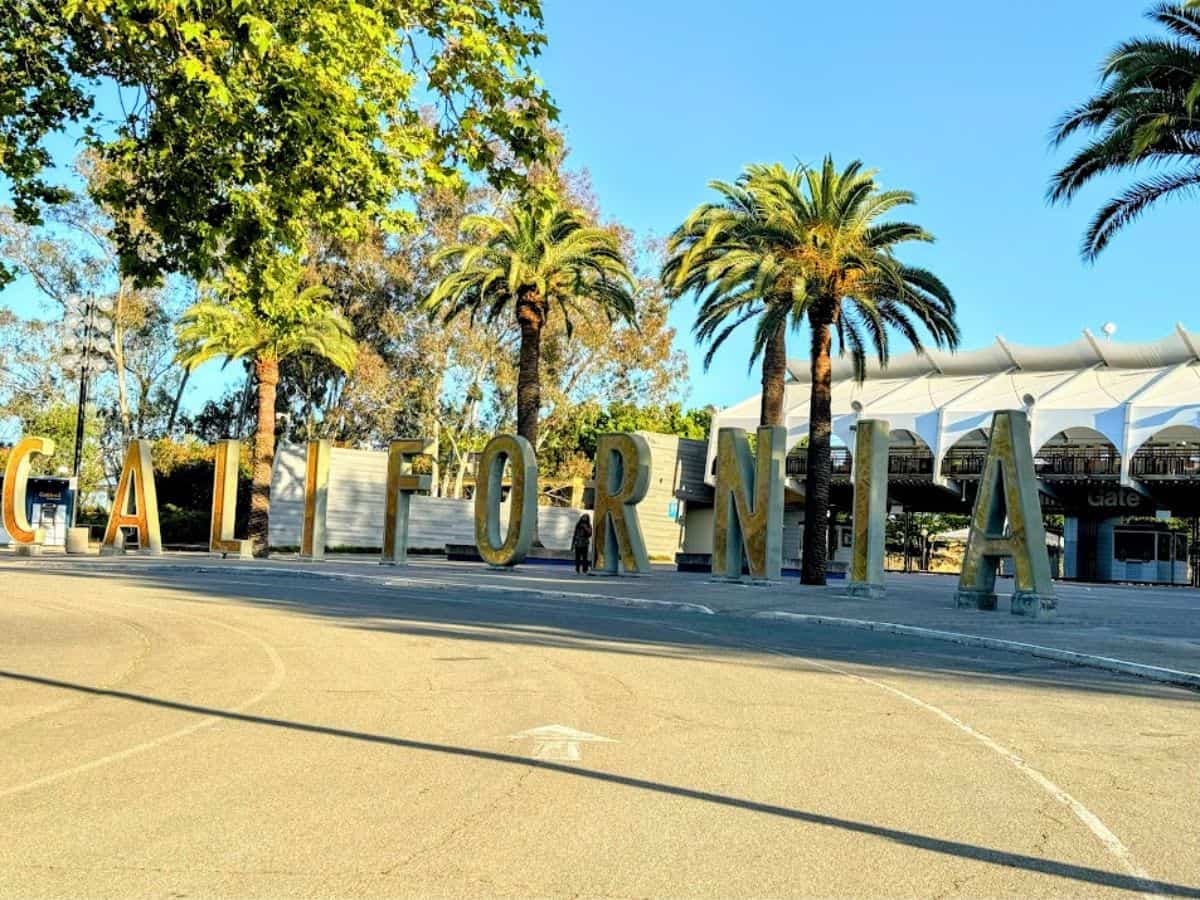 Large gold letters spelling "CALIFORNIA" sit near palm trees and an event venue, a great photo op spot included in the 32 Things To Do In Sacramento list.