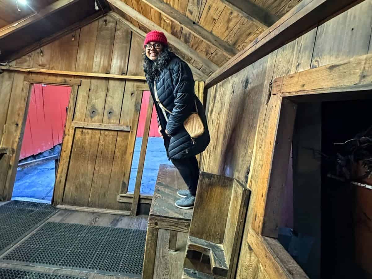 A woman stands inside the famous tilted house at The Mystery Spot, where gravity seems to play tricks. Visiting this optical illusion-filled attraction is one of the 21 Things to Do in Santa Cruz that you can’t miss.