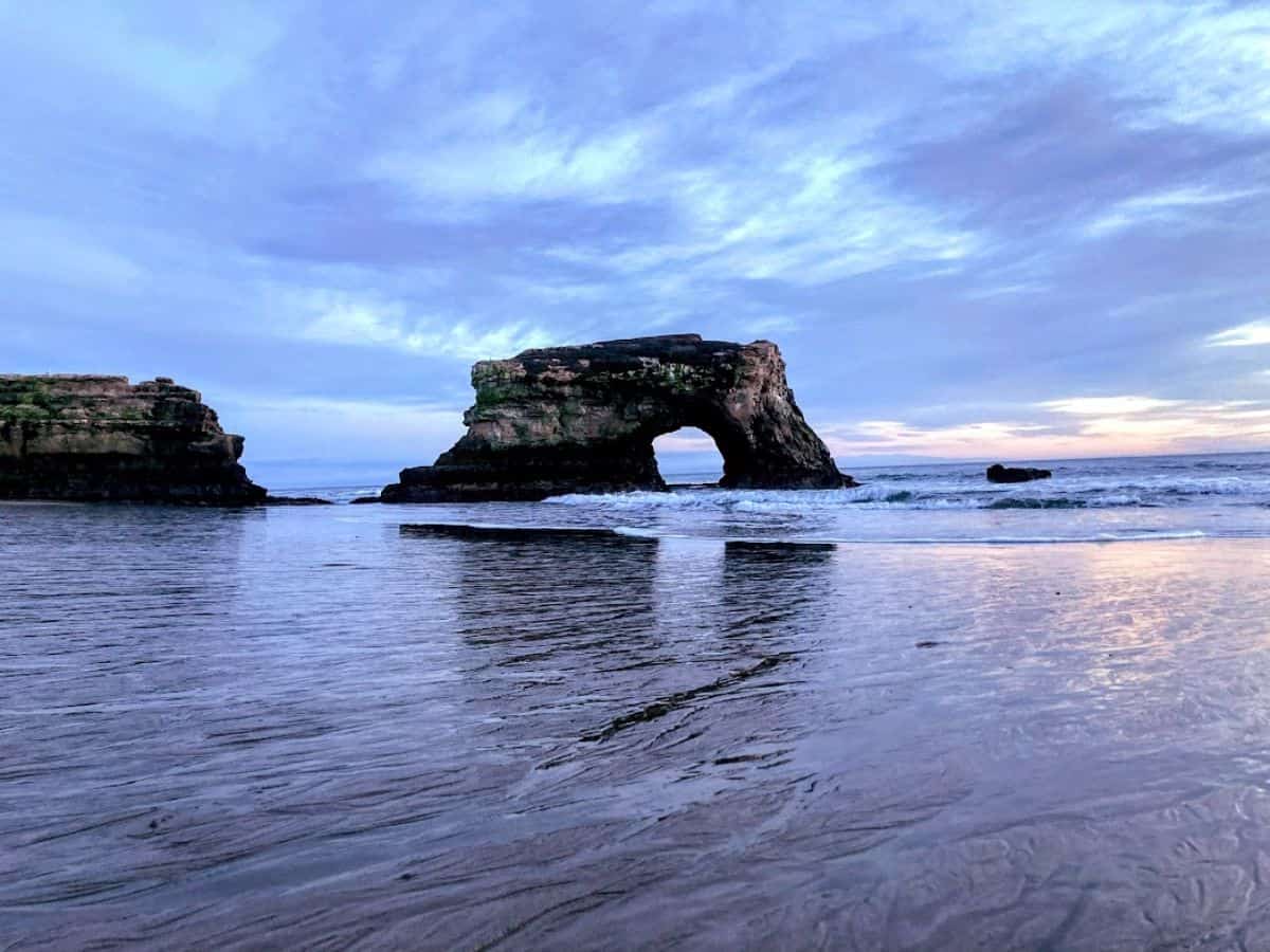 A peaceful view of the rock arch at Natural Bridges State Beach during sunset. This scenic landmark is one of the 21 Things to Do in Santa Cruz, perfect for photography and nature lovers.