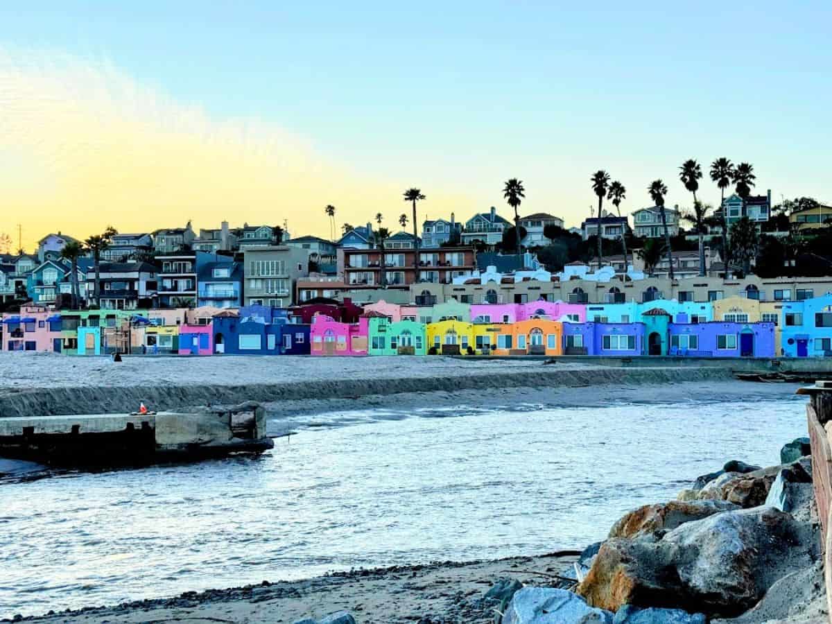 A row of vibrant, pastel-colored beachside cottages stands out against the golden sunset in Capitola. Soaking in the lively charm of this seaside town is one of the best 21 Things to Do in Santa Cruz.