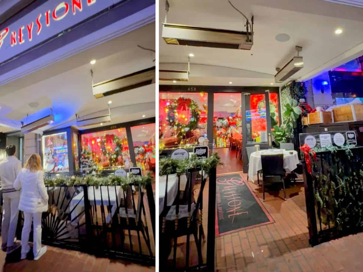 Festively decorated entrance to Greystone Steakhouse in San Diego, glowing with red and white lights and colorful holiday décor seen through the windows and along the outdoor dining area.