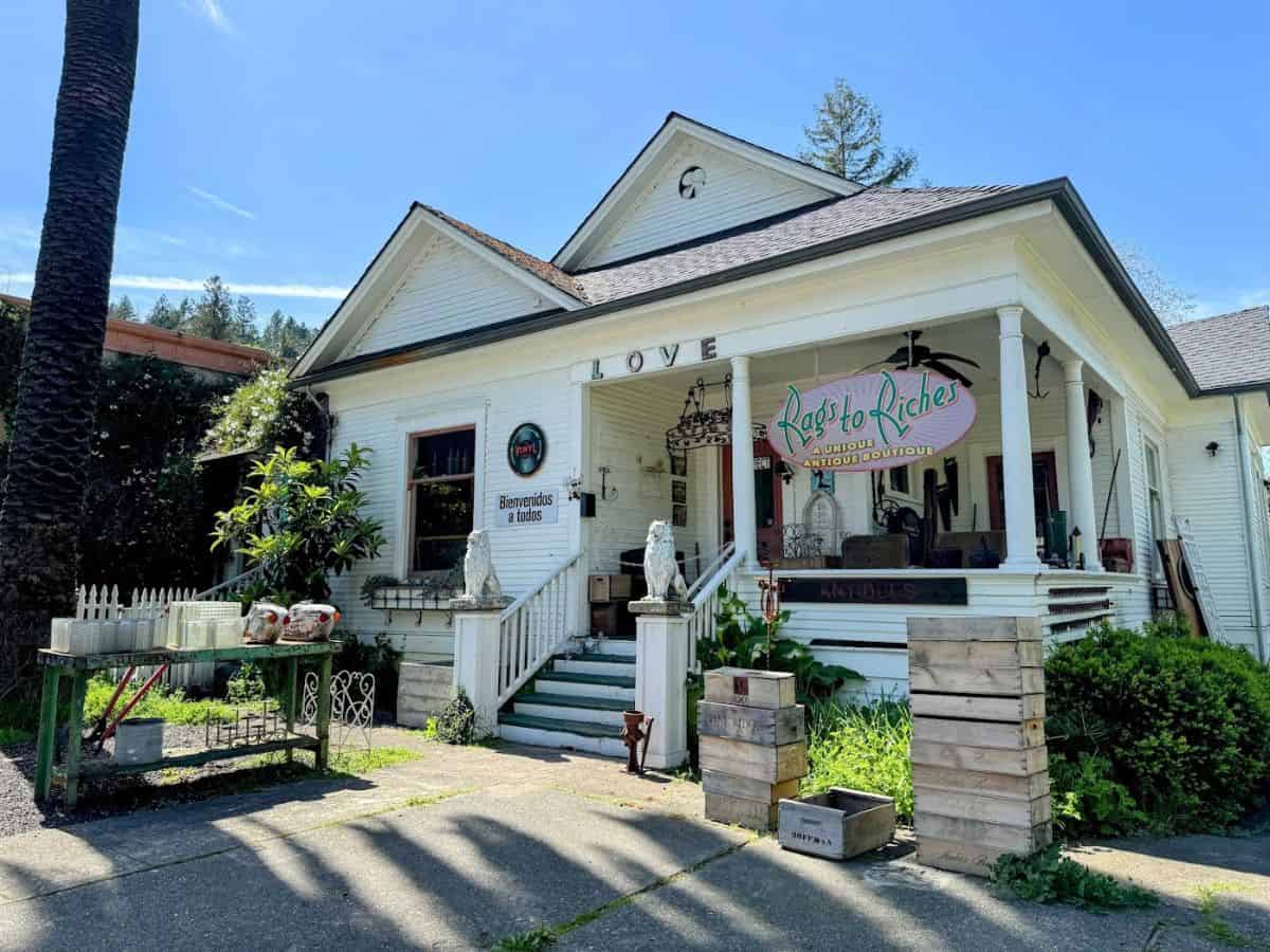 The exterior of Rags to Riches, a charming antique boutique in a white Victorian house with vintage crates and garden decor, offering treasure hunting as one of the top things to do in Calistoga.