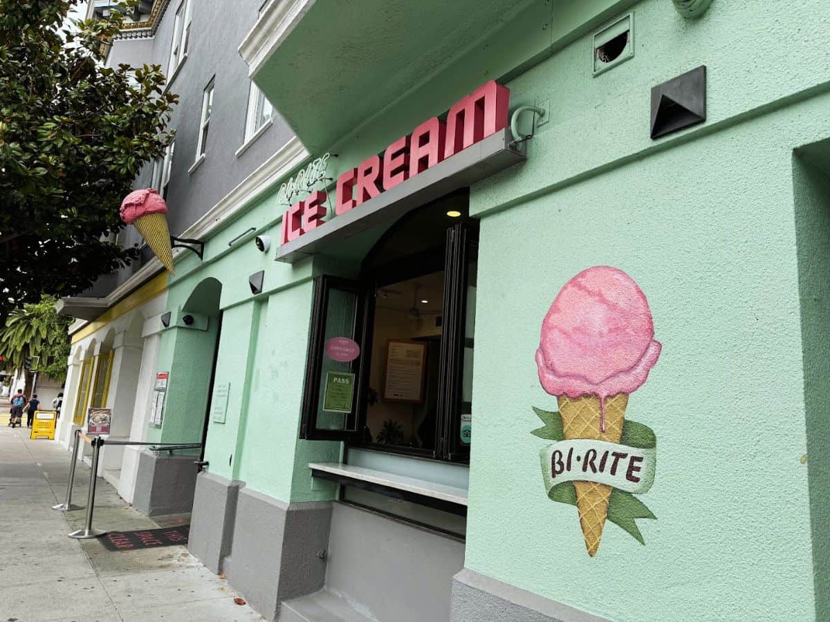 Vibrant mint green ice cream shop exterior with pink signage and wall art.