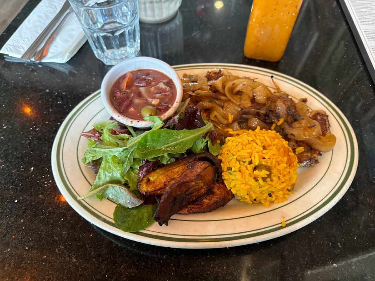A Puerto Rican meal with yellow rice, fried plantains, salad, and Pollo Encebollado at Parada 22, one of the Best Spots to eat in San Francisco.