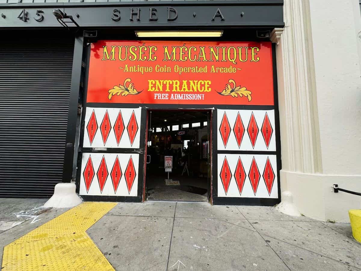 Entrance to Musée Mécanique arcade at Fisherman’s Wharf with red and white painted doors and a free admission sign