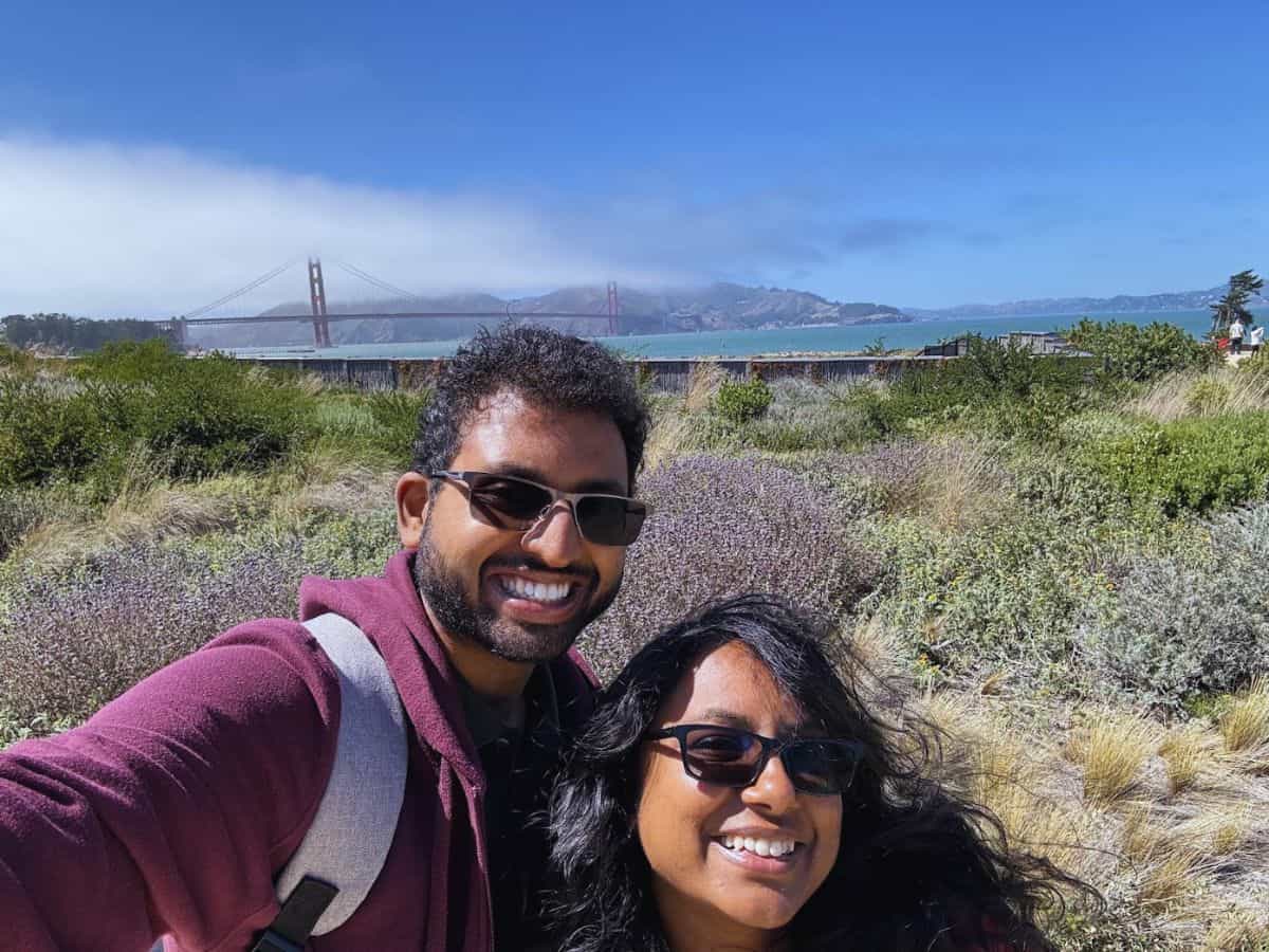 Vibrant couple taking a selfie outdoors with Golden Gate Bridge in the background, exploring scenic Bay Area and beyond.